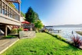 Furnished back patio with red chairs, grass, and water view. Waterfront back yard, Royalty Free Stock Photo