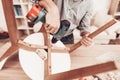 Furniture Assembler with Drill in Hands Repairs Chair. Royalty Free Stock Photo