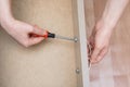 Furniture assembly.Hands of the girl close up. Screws screwdriver handle dresser