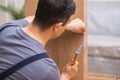 Furniture assembly and shipping master hammering nail into wooden wardrobe in apartment