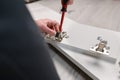 Furniture assembly. A worker inserts and adjusts a hinge into a wooden cabinet door.Adjustment of fittings, door hinges.