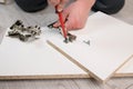 Furniture assembly. The worker inserts the loop and tightens it with a screwdriver. Adjustment of fittings, door hinges.