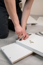 Furniture assembly. A worker is screwing a hinge into a wooden closet door. Adjustment of fittings, door hinges.