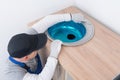 A furniture collector in a protective uniform inserts a metal sink into a cut-out hole in the countertop of kitchen furniture