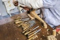 Furniture manufacturing with joiner tools, wood shavings and carpenter, working with chisel at the background.