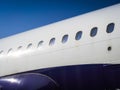 Fuselage of airplane with door and windows. Row of portholes outside the passenger aircraft. Plane on bly sky background Royalty Free Stock Photo