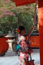 Japanese girl in Kimono dress stand and catch fabric rope to ringing the bell for bless at Fushimi Inari Shrine. Royalty Free Stock Photo