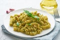 Fusili pasta with basil pesto and herbs, italian cuisine, gray stone background, closeup
