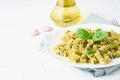 Fusili pasta with basil pesto and herbs, italian cuisine, gray stone background, side view