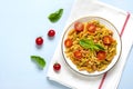 Fusilli - classic italian pasta from durum wheat with chicken meat, tomatoes cherry, basil in tomato sauce in white bowl on blue w Royalty Free Stock Photo