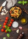 Fusilli pasta in black bowl with parmesan cheese and tomatoes, oil and garlic with basil and linen towel on wooden background Royalty Free Stock Photo