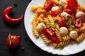 pasta salad with tomato, pepper and mozzarella balls in plate on dark wooden background Royalty Free Stock Photo