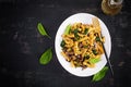 Fusilli pasta with spinach and mushrooms on a white plate. Vegetarian / vegan food.
