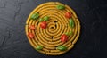 Fusilli pasta spirals are arranged in a circular pattern on a textured black surface. Cherry tomato Royalty Free Stock Photo