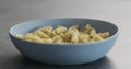 Fusilli pesto pasta in blue bowl on concrete background