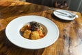 Fusion spaghetti topped with ebiko and seaweed Attached with fried breaded meat. in a white round plate on a wooden table There