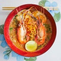 Fusion spicy thai-chinese food in thailand by top view, Tom yum koong-noodle in soup  with topping of shrimps boiled egg parsley Royalty Free Stock Photo