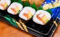 Futomaki, appetizing sushi roll with cucumber, salmon, egg, imitation crab stick and seaweed. Serving on black plastic plate from Royalty Free Stock Photo