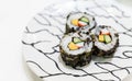 Futomaki, appetizing sushi roll with cucumber, salmon, egg, imitation crab stick and seaweed. Serving on white plate