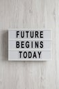 `Future begins today` words on a lightbox on a white wooden background, top view. Overhead, from above, flat lay