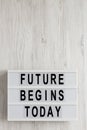 `Future begins today` words on a lightbox on a white wooden surface, top view. Overhead, from above, flat lay. Copy space