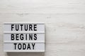 `Future begins today` words on a lightbox on a white wooden surface, top view. Overhead, from above, flat lay. Space for text