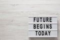 `Future begins today` words on a modern board on a white wooden background, top view. Overhead, from above, flat lay. Copy space