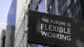 The Future is Flexible Working on a black city-center sign in front of a modern office building