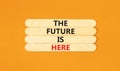 The future is here symbol. Concept words The future is here on wooden stick. Beautiful orange table orange background.