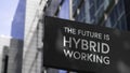 The Future is Hybrid Working on a black city-center sign in front of a modern office building