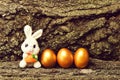 Rabbit toy, golden easter eggs on tree bark background Royalty Free Stock Photo