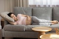 Future mother sleep on sofa holding palm on naked belly