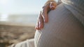 Future mother stroking tummy on sunset beach closeup. Woman hand caressing belly