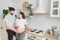 Future parents embrace standing in the kitchen