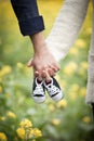 Future parents holding hands and a pair of little shoes Royalty Free Stock Photo