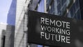 The Future is Remote Working on a black city-center sign in front of a modern office building