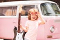 Future rock star. Excited child in pink shirt with electric guitar over pink background. Kids music.