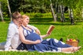 Future young parents reading the book on picnic Royalty Free Stock Photo