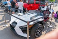 A futuristic, angular vehicle is displayed at an outdoor exhibition, with a protective barrier surrounding it The