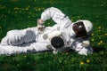 Futuristic astronaut in a helmet sits on a green lawn among flowers