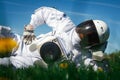 Futuristic astronaut in a helmet sits on a green lawn among flowers