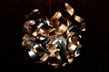 Metal ribbon chandelier closeup. Modern lampshade. Copper and silver textured background. Abstract chaotic pattern.