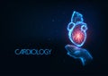 Futuristic Cardiology concept with glowing low polygonal human hand holding heart organ hologram