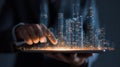Futuristic cityscape hologram projected from tablet with hand interacting, glowing skyscraper lights, technology concept Royalty Free Stock Photo