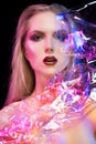Futuristic conceptual portrait of a beautiful girl covered by wrinkled transparent plastic colored by blue and red lights Royalty Free Stock Photo