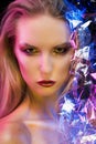 Futuristic conceptual portrait of a beautiful girl covered by wrinkled transparent plastic colored by blue and red lights