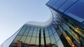 Futuristic curved glass building, clear sky.