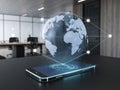 Futuristic global communication concept with holographic earth above smartphone in office setting Royalty Free Stock Photo