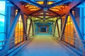 A futuristic pedestrian overpass over a motorway made from a glass steel overpass