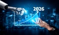 Futuristic Robot Hand Analyzing Data Trends for 2026 with Human Hand Reaching Out Over Digital Business Background Royalty Free Stock Photo